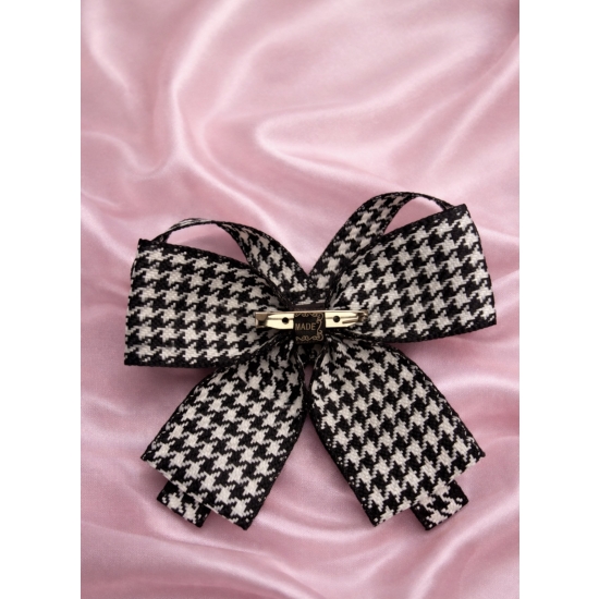 Elegancka broszka w formie kokardy w klasyczny wzór pepitki, wykończona perłowym środkiem – ponadczasowy dodatek do stylowych stylizacji.